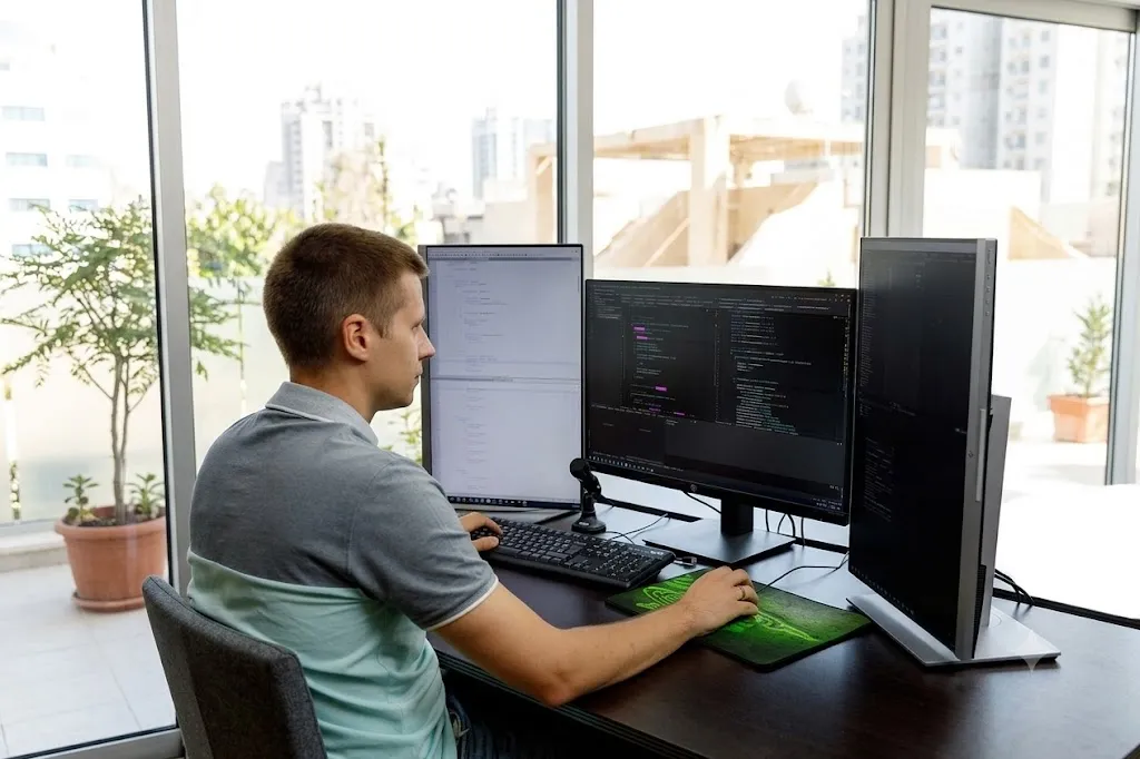 A developer coding by the floor-to-ceiling windows