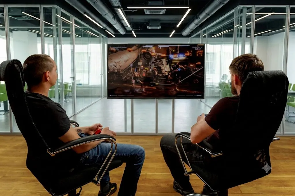 Two teammates playing a fighting game on the big screen